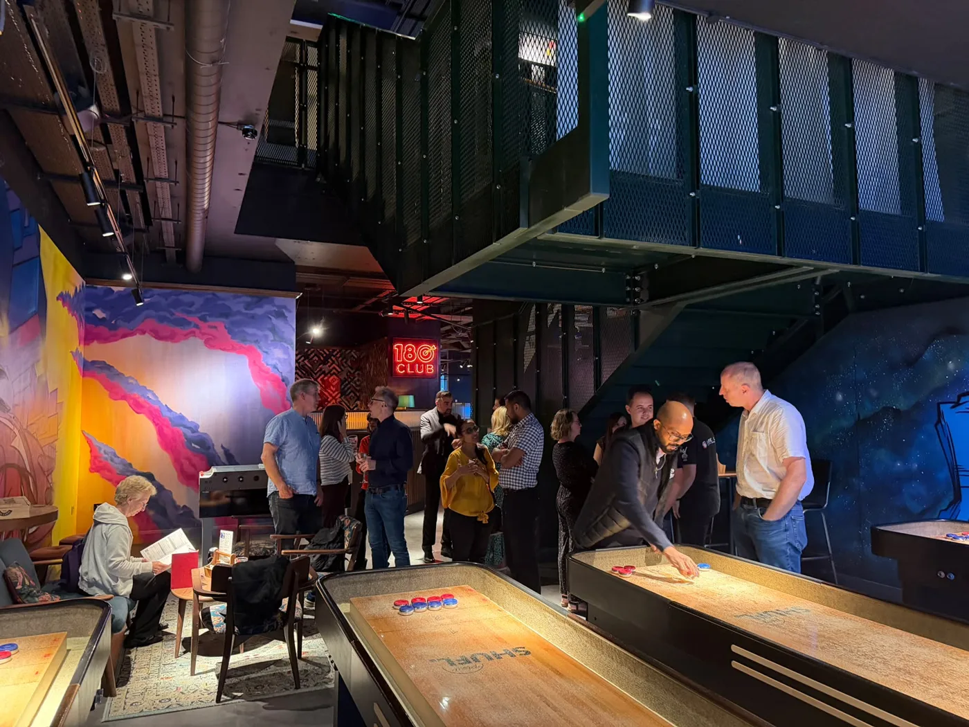 Guild members gathered around a shuffleboard table, one leaning over to play